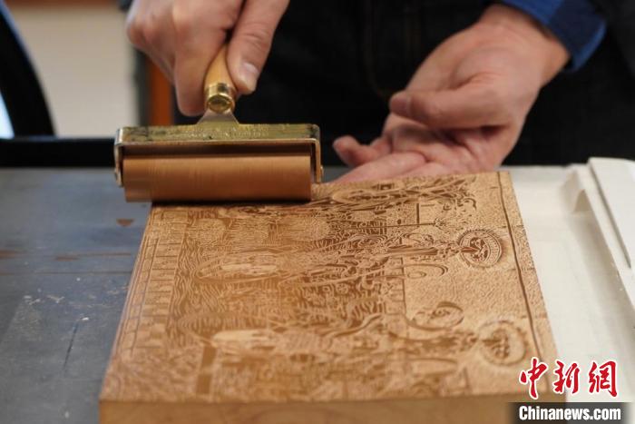 圖為徐晉林工作室工作人員正在給雕好壁畫的版面滾油墨?！【琶赖┰?　攝