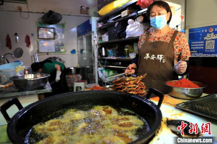 圖為平安驛·河湟民俗文化體驗(yàn)地內(nèi)的商戶炸干板魚。　薛蒂 攝